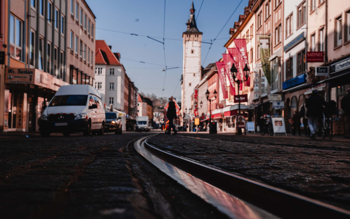 Die Domstraße in Würzburg im Vordergrund die Straßenbahngleise im Hintergrund das Rathaus mit dem Grafeneckart Die Domstraße in Würzburg im Vordergrund die Straßenbahngleise im Hintergrund das Rathaus mit dem Grafeneckart